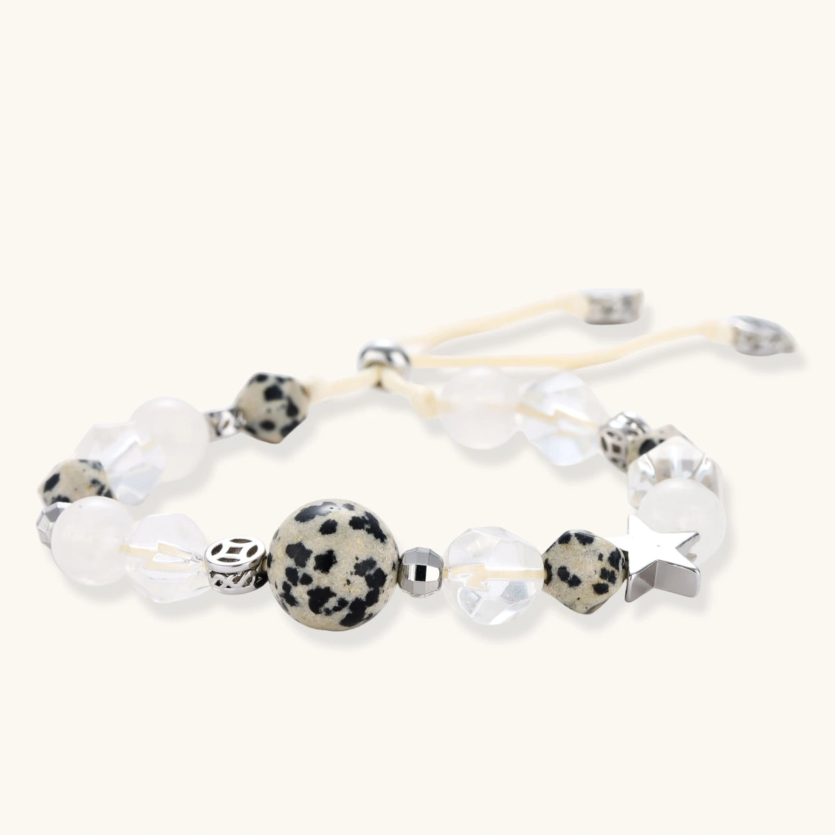 Adjustable beaded bracelet with spotted dalmatian stones, clear quartz crystals, and silver star charm on white background.