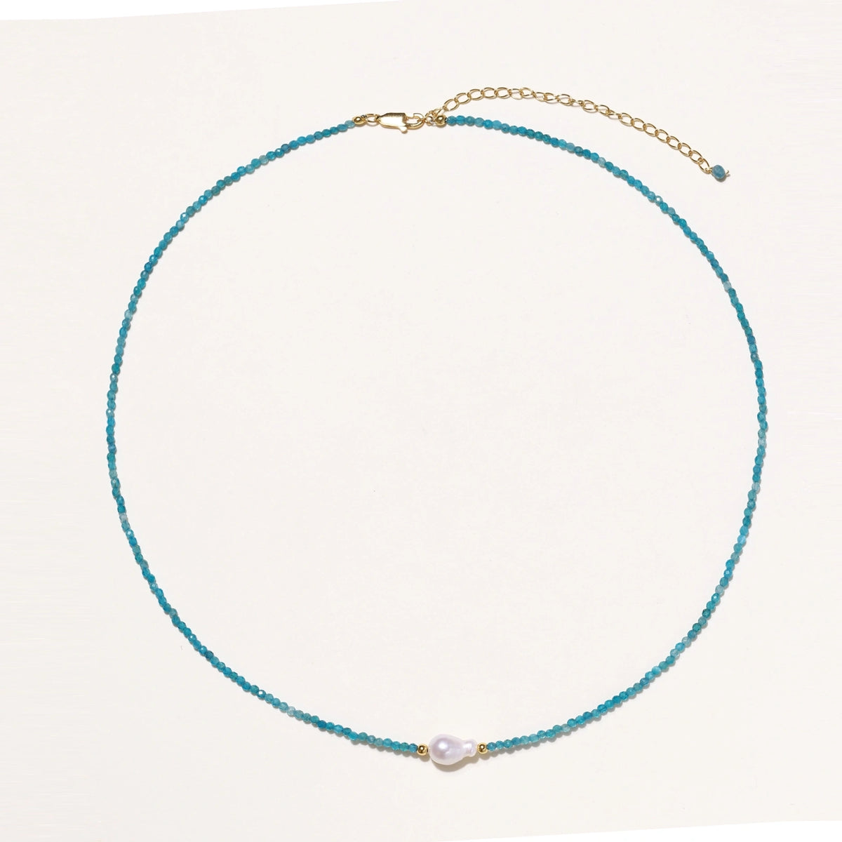 Dainty teal apatite beaded necklace with a single freshwater pearl centerpiece flanked by two small gold beads, adjustable gold clasp.