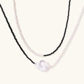 Double-strand necklace with black faceted quartz and white pearls featuring an oversized baroque pearl centerpiece